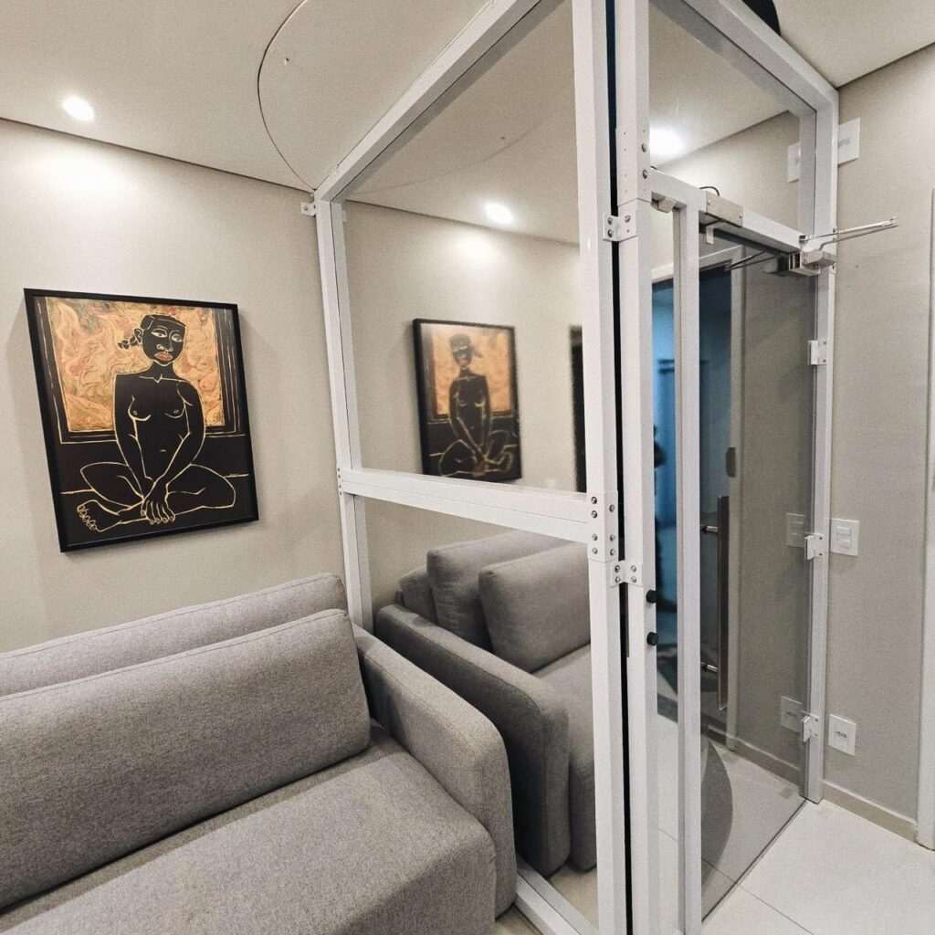 Elevador residencial Tonela com cabine de vidro instalado na sala de um apartamento