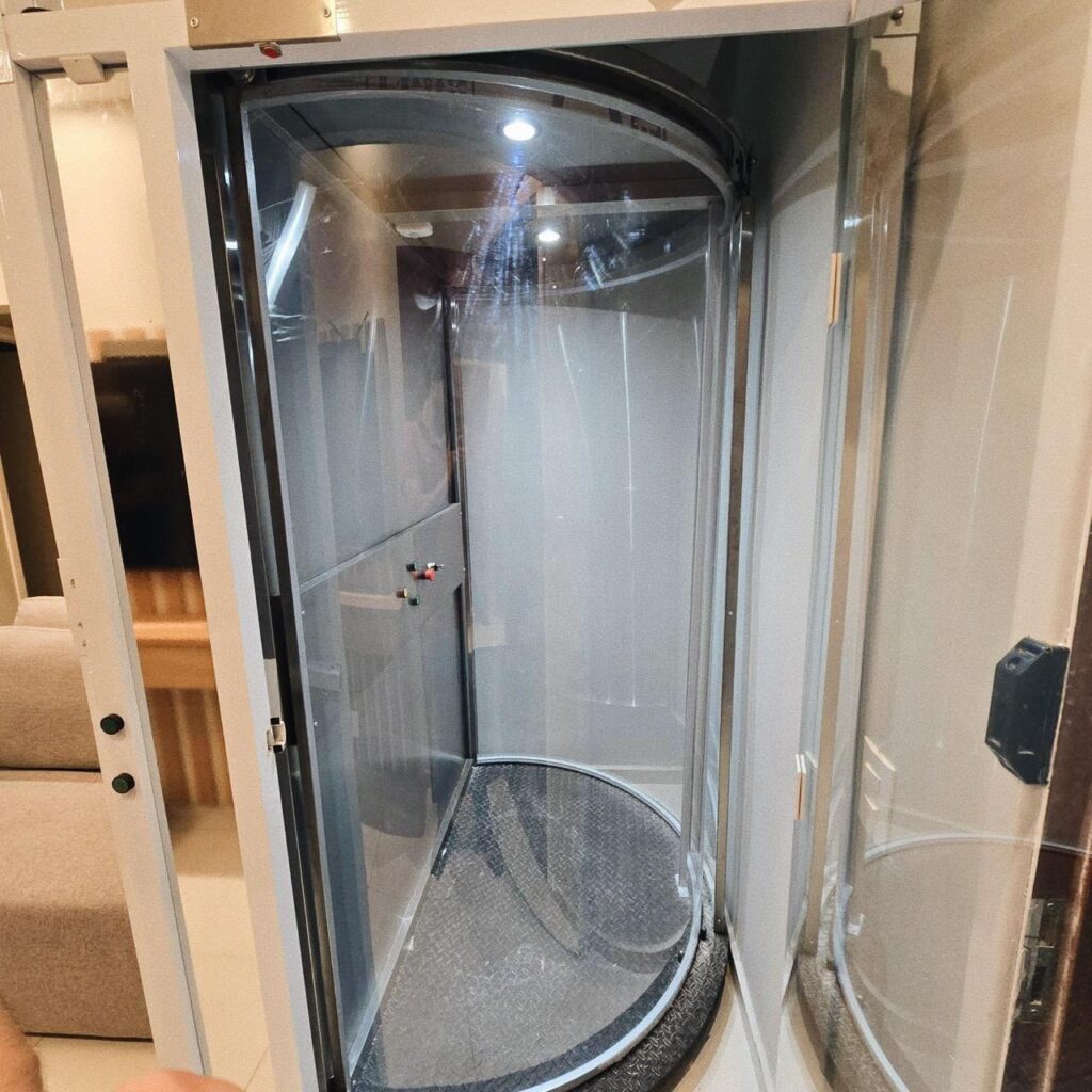 Elevador residencial Tonela de cabine cilíndrica em vidro, com a porta aberta