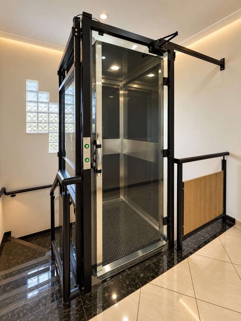 Plataforma de acessibilidade Tonela com estrutura preta e cabine de vidro no vão da escada